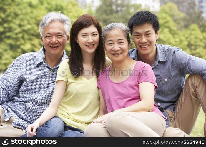 Portrait Of Chinese Parents With Adult Children Relaxing In Park Together