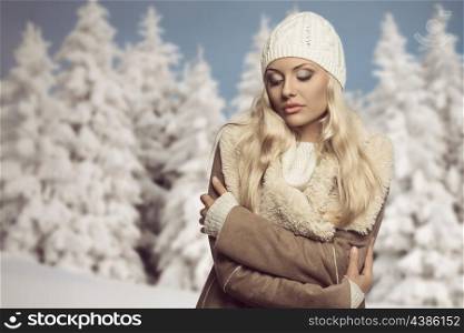 portrait of cold blonde woman in winter season. She wearing warm clothes, white wool cap, sweater and hot coat