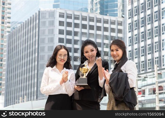 Portrait Of Colleagues With Trophy Standing In City