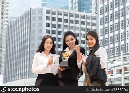 Portrait Of Colleagues With Trophy Standing In City