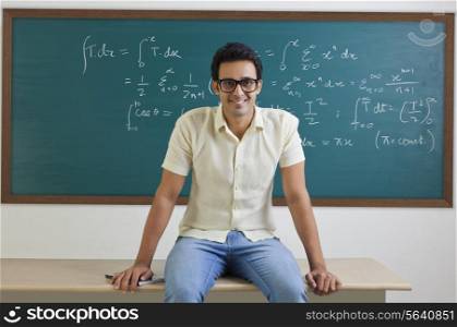 Portrait of college student sitting on a table smiling