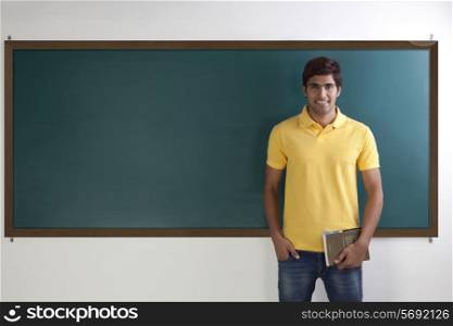 Portrait of college student standing in front of blackboard