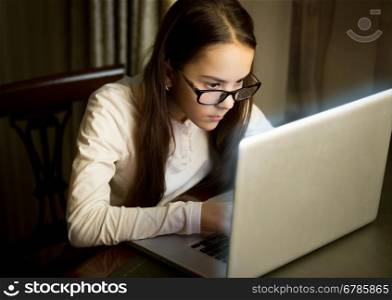 Portrait of concentrated schoolgirl typing message on laptop