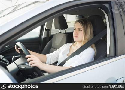 Portrait of concentrated young blonde woman driving car