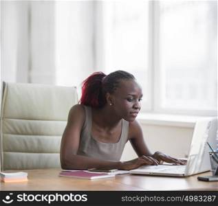 Portrait of confident african business woman sitting at the table and typing a document on the laptop