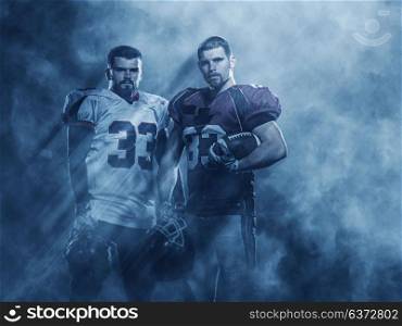 portrait of confident American football players holding ball while standing on the field with lights and smoke aroung