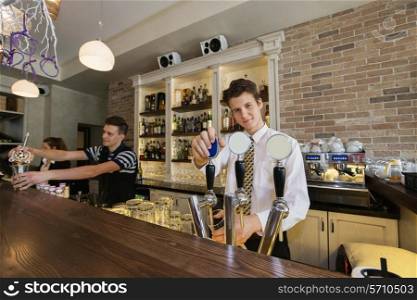 Portrait of confident bartender at counter with coworkers in background