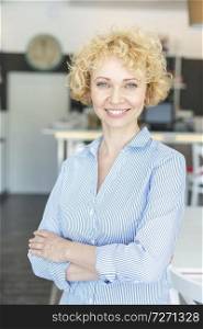 Portrait of confident blond owner standing with arms crossed at restaurant