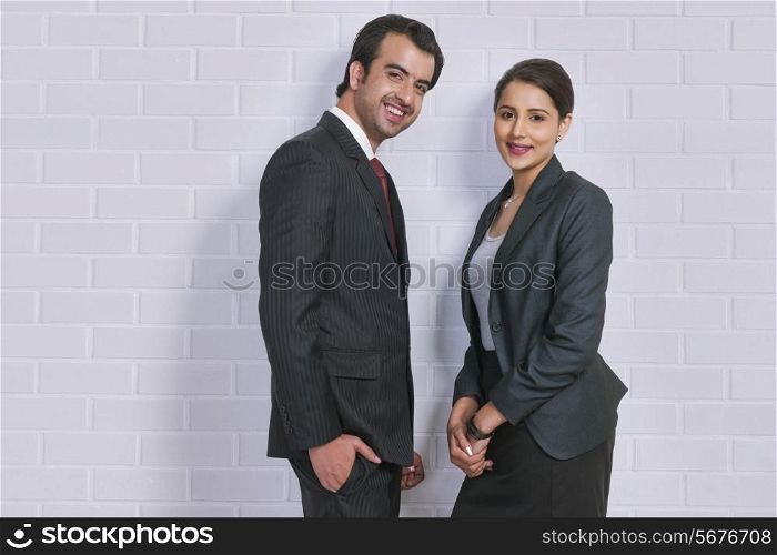 Portrait of confident business colleagues standing against wall in office