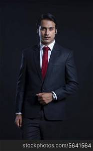 Portrait of confident businessman against black background