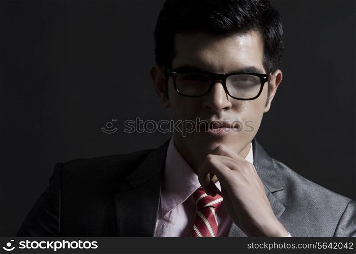 Portrait of confident businessman against black background