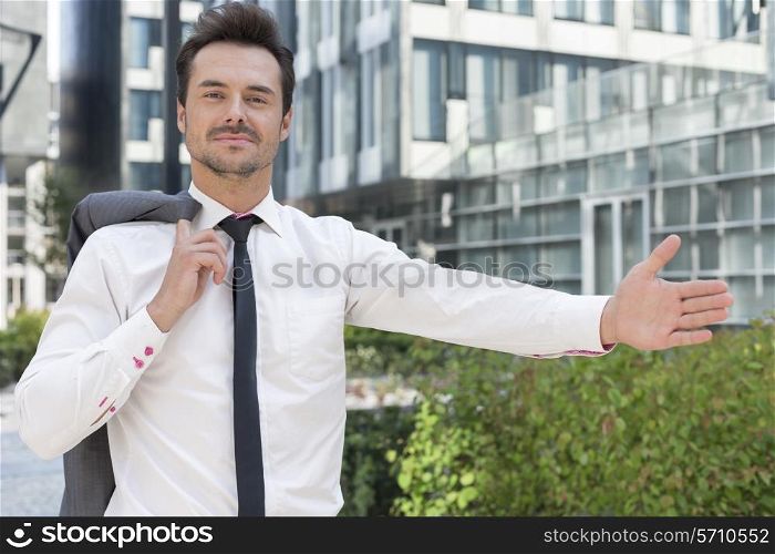 Portrait of confident businessman gesturing while standing outside office building