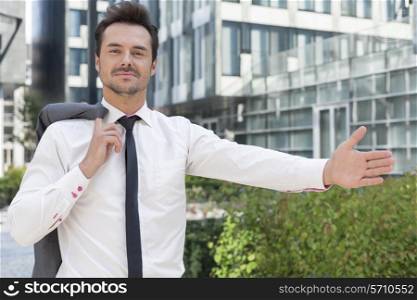 Portrait of confident businessman gesturing while standing outside office building