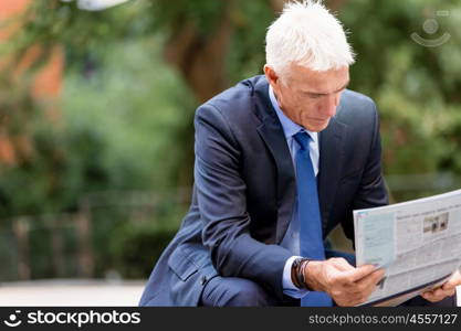 Portrait of confident businessman outdoors. Portrait of confident businessman reading papers outdoors