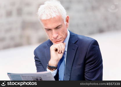 Portrait of confident businessman outdoors. Portrait of confident businessman reading papers outdoors