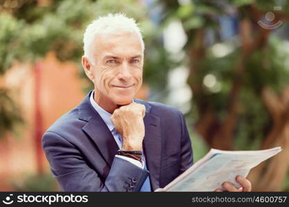 Portrait of confident businessman outdoors. Portrait of confident businessman reading papers outdoors