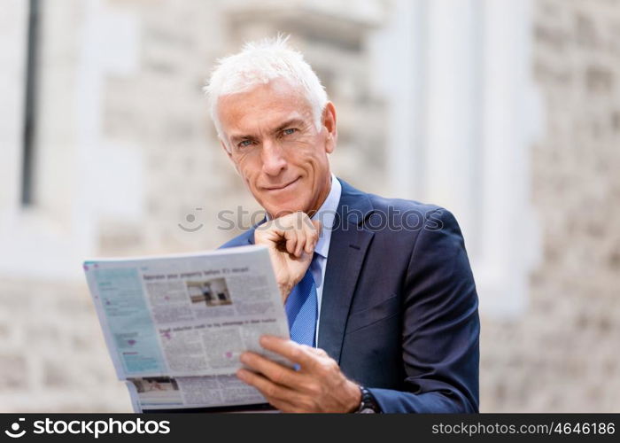 Portrait of confident businessman outdoors. Portrait of confident businessman reading papers outdoors