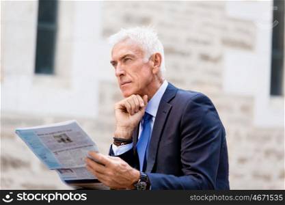 Portrait of confident businessman outdoors. Portrait of confident businessman reading papers outdoors