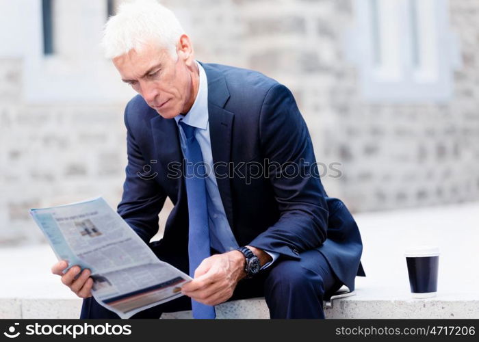 Portrait of confident businessman outdoors. Portrait of confident businessman reading papers outdoors