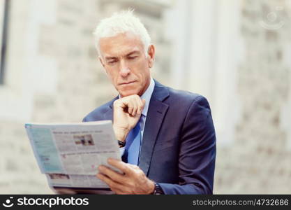 Portrait of confident businessman outdoors. Portrait of confident businessman reading papers outdoors