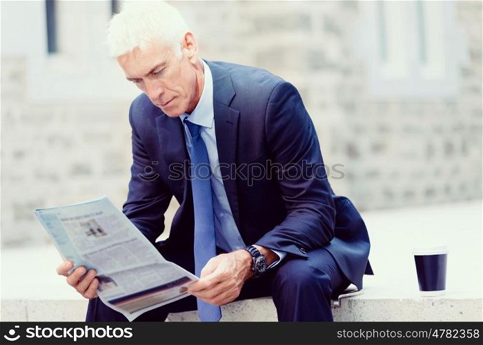 Portrait of confident businessman outdoors. Portrait of confident businessman reading papers outdoors