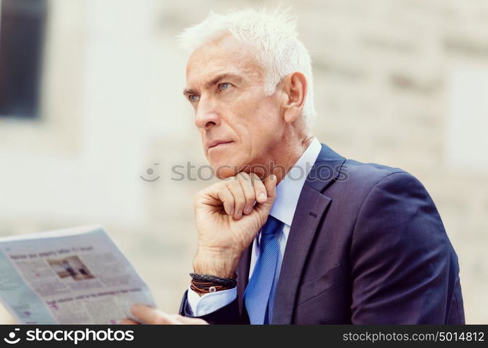 Portrait of confident businessman outdoors. Portrait of confident businessman reading papers outdoors