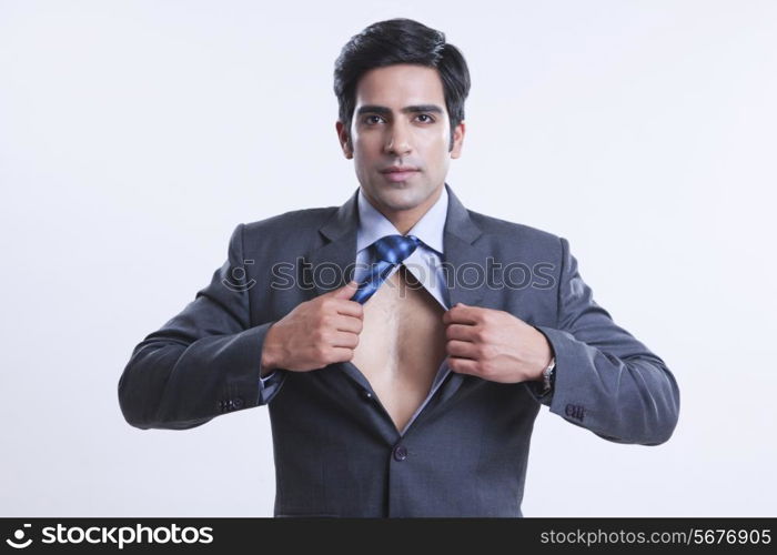 Portrait of confident businessman showing chest over gray background