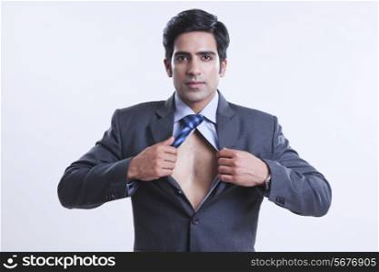 Portrait of confident businessman showing chest over gray background