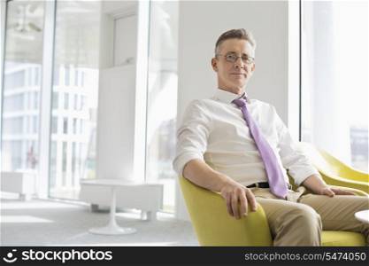 Portrait of confident businessman sitting at office lobby