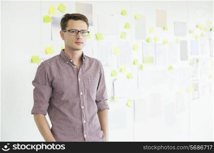 Portrait of confident businessman standing against whiteboard in creative office