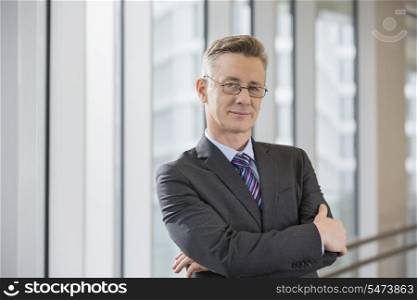 Portrait of confident businessman standing arms crossed in office