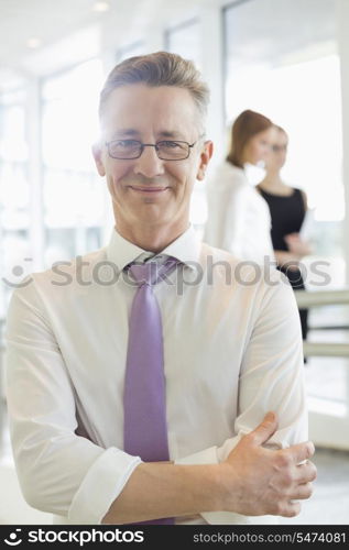 Portrait of confident businessman standing arms crossed in office