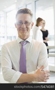 Portrait of confident businessman standing arms crossed in office