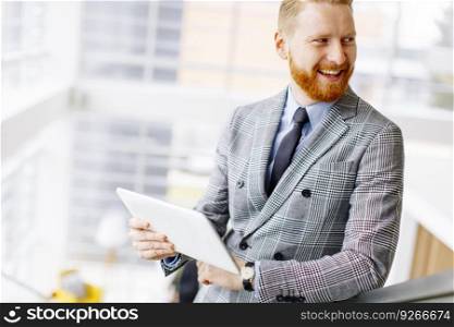 Portrait of confident businessman using tablet on office stairs