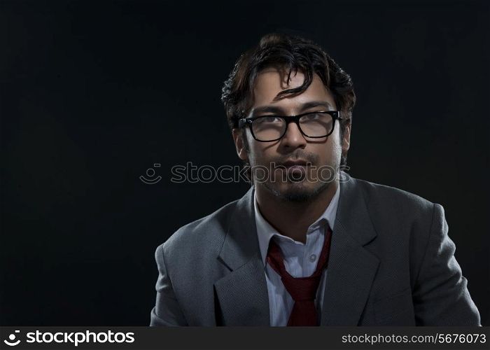 Portrait of confident businessman wearing glasses against black background