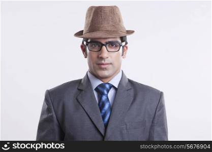 Portrait of confident businessman wearing hat and glasses against gray background