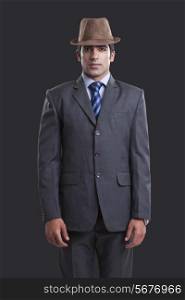 Portrait of confident businessman wearing hat over black background