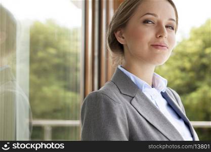 Portrait of confident businesswoman by glass door