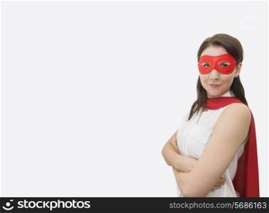 Portrait of confident businesswoman dressed as superhero standing arms crossed in office