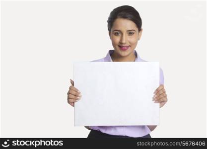 Portrait of confident businesswoman holding blank placard against white background
