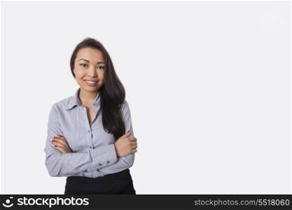 Portrait of confident businesswoman standing arms crossed against gray background