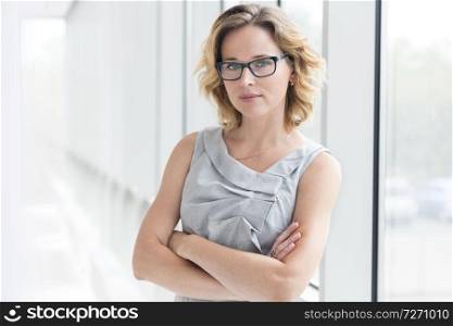 Portrait of confident businesswoman standing with arms crossed at new office