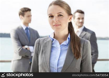 Portrait of confident businesswoman standing with coworkers in background on terrace