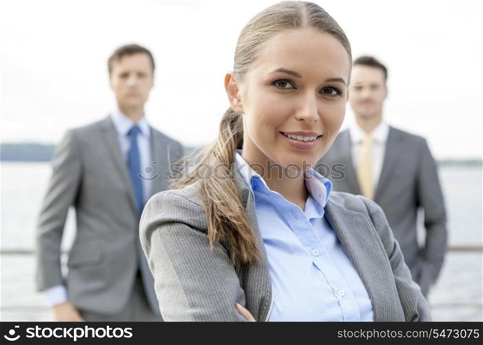 Portrait of confident businesswoman standing with coworkers on terrace