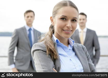Portrait of confident businesswoman standing with coworkers on terrace