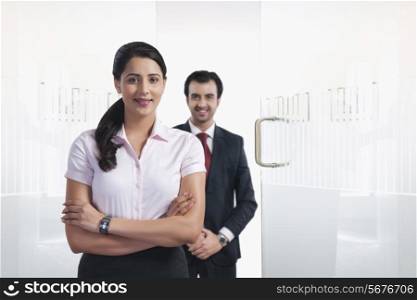 Portrait of confident businesswoman with colleague in background at office