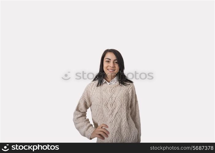 Portrait of confident businesswoman with hand on hip standing against gray background