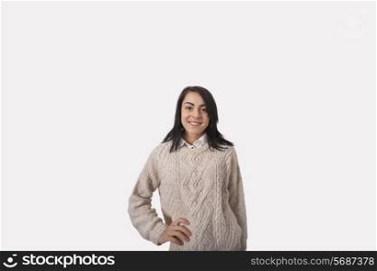 Portrait of confident businesswoman with hand on hip standing against gray background