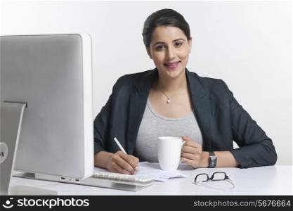 Portrait of confident businesswoman working at desk over white background