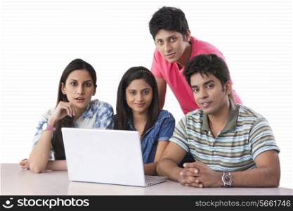 Portrait of confident college students with laptop in library